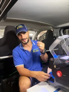 Gold Coast locksmith cutting a car key replacement at night from the mobile van