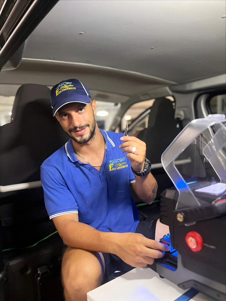 Gold Coast locksmith cutting a car key replacement at night from the mobile van